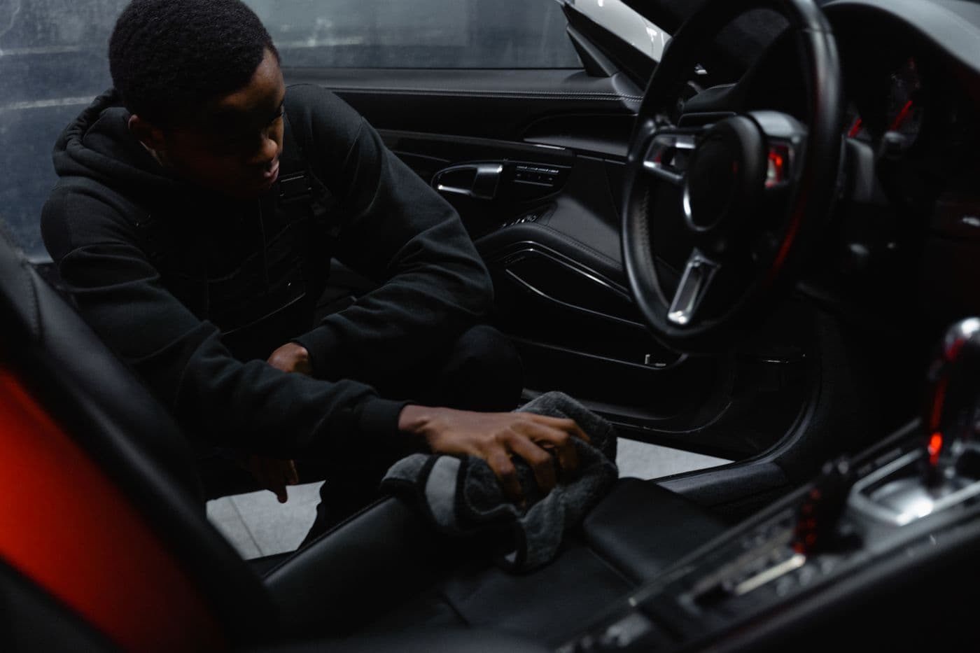 Detailer cleaning a car seat with a cloth during an interior detail