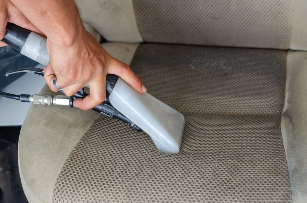 Vacuuming a fabric car seat during an interior detail