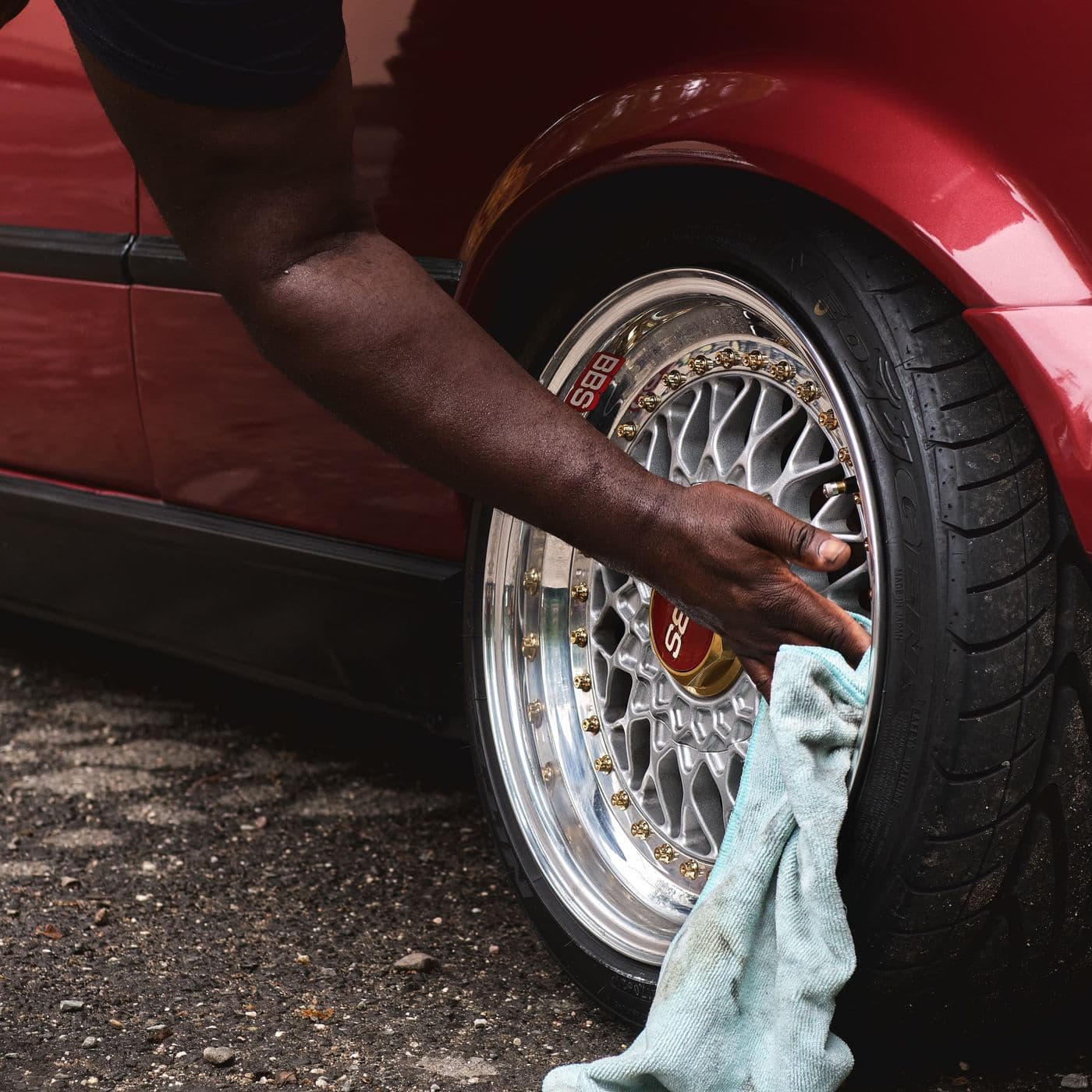 Detailer cleaning an alloy car wheel with a cloth