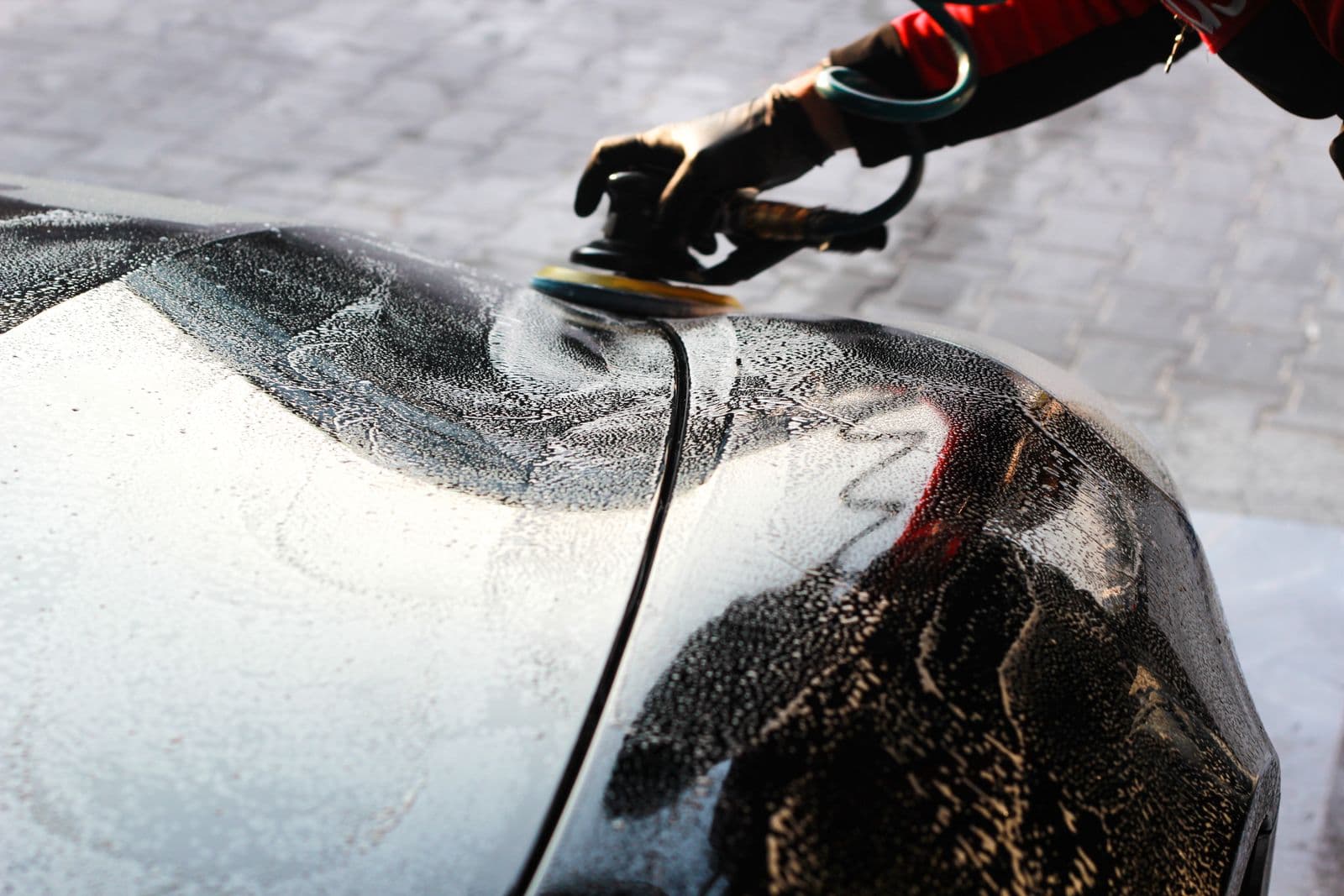 Close-up of paint being machine-polished, showing improved gloss and reflection